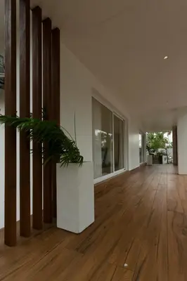 a living room with wooden floors and a plant at Ocean Whisper- psst! hidden gem in Kaipamangalam