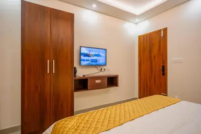 a bedroom with a bed and a tv on a wall at Metro Residency in Tirūr