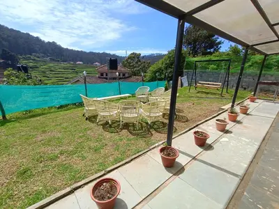 a patio with a table and chairs and a fence at Mountain View Private Villa in Ooty
