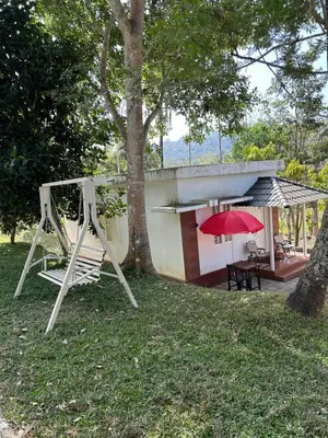 a house with a red umbrella and a swing at Mahogany by Exuberance Stays in Wayanad
