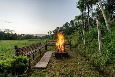 a fire pit in a field next to a bench at Mahogany by Exuberance Stays in Wayanad