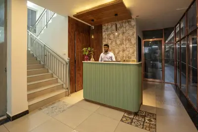 a man standing behind a green counter in a hallway at BR Residency in Trichūr