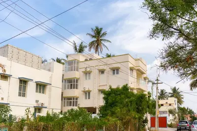 a white building with a palm tree behind it at Thapovan coimbatore in Coimbatore