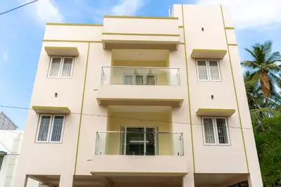 a building in front of a palm tree at Thapovan coimbatore in Coimbatore