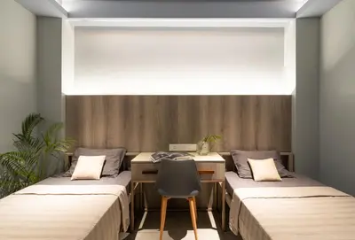 two beds in a room with a desk and a chair at YMCA International Guest House in Trichūr