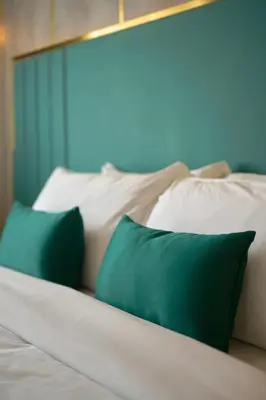 a bed with two green pillows on it at Kowju Airport Hotel Calicut in Kondotti