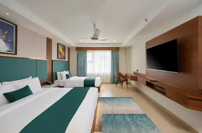 a hotel room with two beds and a flat screen tv at Kowju Airport Hotel Calicut in Kondotti
