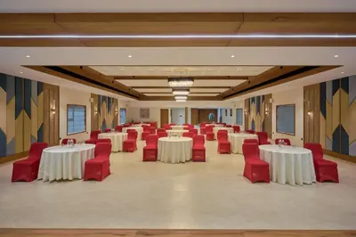 a banquet hall with white tables and red chairs at Kowju Airport Hotel Calicut in Kondotti