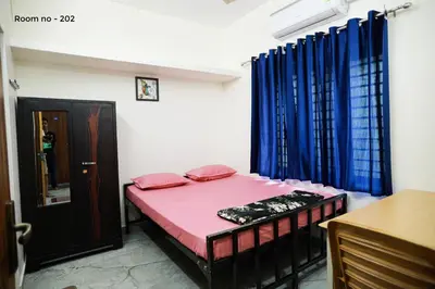 a small room with a bed and blue curtains at Ganga Homes Rooms Only in Trichūr