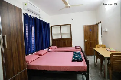 a room with two beds and a table in it at Ganga Homes Rooms Only in Trichūr