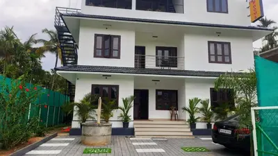 a white house with a staircase in front of it at Brighton Retreat in Sultan Bathery