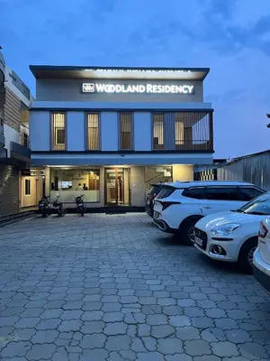 a building with cars parked in a parking lot at Woodland residency in Mettuppālaiyam