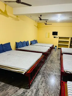 three beds in a room with yellow walls at Woodland residency in Mettuppālaiyam