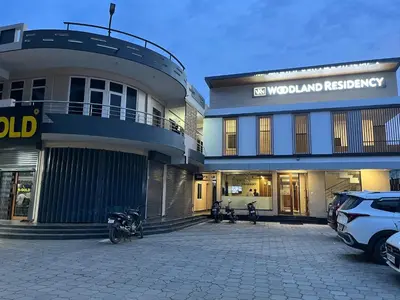 a building with two motorcycles parked in a parking lot at Woodland residency in Mettuppālaiyam