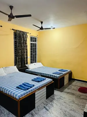 two beds in a room with yellow walls at Woodland residency in Mettuppālaiyam