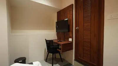 a room with a desk with a chair and a television at Hotel Hive Inn - Kozhikode in Kozhikode