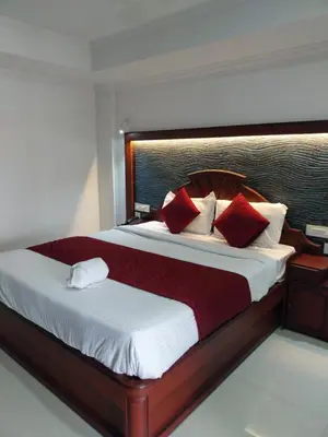 a bedroom with a large bed with red pillows at Hotel Savera Park in Trichūr
