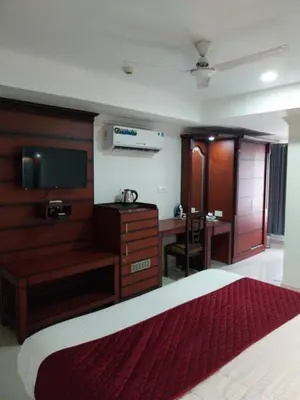 a bedroom with a bed and a desk and a television at Hotel Savera Park in Trichūr