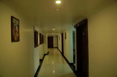 a hallway with white walls and a long hallway with paintings at Hotel Savera Park in Trichūr