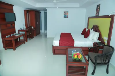 a bedroom with a bed and a table with flowers on it at Hotel Savera Park in Trichūr
