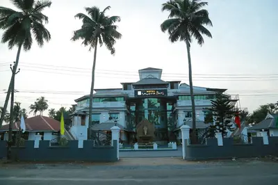 a building with palm trees in front of it at Hotel Savera Park in Trichūr