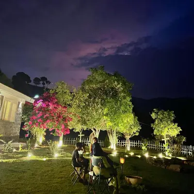 two people sitting at a table in a yard at night at Earth songs by Green leaves - 10 kms from kotagiri in Kotagiri