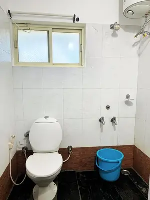 a bathroom with a toilet and a blue bucket at Earth songs by Green leaves - 10 kms from kotagiri in Kotagiri