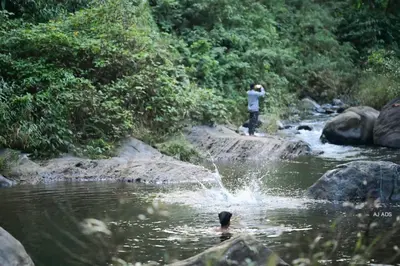 a man is standing in the water in a river at BLUE CREEK in Meppādi