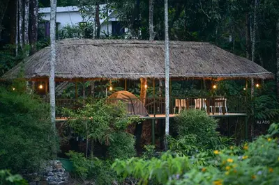 a hut with a deck with chairs and lights at BLUE CREEK resort in Meppādi