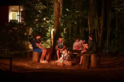 a group of people sitting around a fire at BLUE CREEK resort in Meppādi