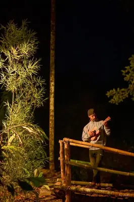 a man sitting on a bench with a guitar at BLUE CREEK resort in Meppādi
