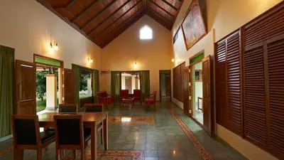a dining room with a wooden table and chairs at Silvertrails in Kalpetta