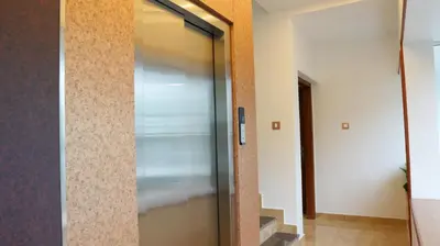 a glass elevator door in a hallway at Neom's Golden Gate in Alwaye
