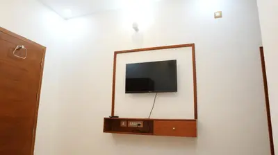 a mirror on a wall with a tv in it at Neom's Golden Gate in Alwaye