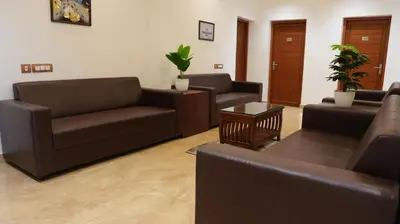 a living room with couches and chairs and a table at Neom's Golden Gate in Alwaye