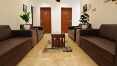 a waiting room with brown couches and a table at Neom's Golden Gate in Alwaye