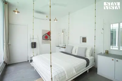 a white bedroom with a swinging bed in it at StayVista at Reflection by The Woods - Breakfast Included - Luxury Villa in Madikeri