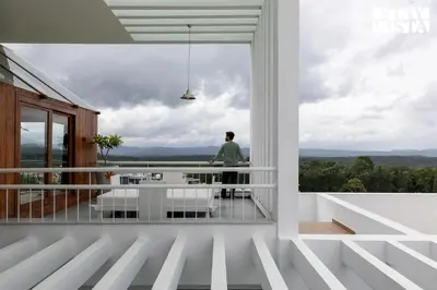 a man standing on the balcony of a house at StayVista at Reflection by The Woods - Breakfast Included - Luxury Villa in Madikeri