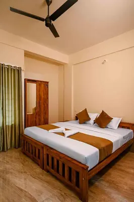 a bedroom with a large bed with a ceiling fan at Spectrum stays in Ambalavayal