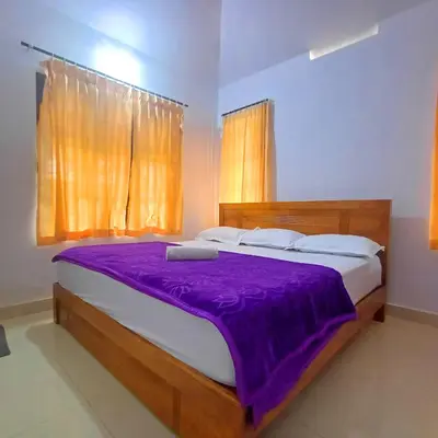 a bedroom with a large bed with a purple blanket at Wayanad Empire Budget Villa in Kalpetta