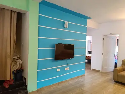 a living room with a blue wall with a flat screen tv at Forest Gate villa in Ooty