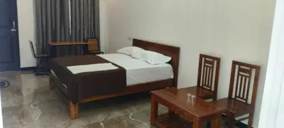 a bedroom with a bed and a table and a bed sidx sidx sidx at Dream Nest Resort in Mettuppālaiyam