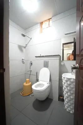 a bathroom with a white toilet and a sink at Nandan Enclave in Mysore