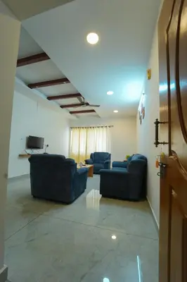 a living room with two blue couches and a tv at Nandan Enclave in Mysore