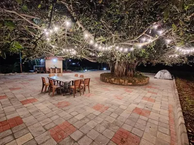 a table and chairs under a tree with lights at Aadvik Luxury Farmstay in Antarasante