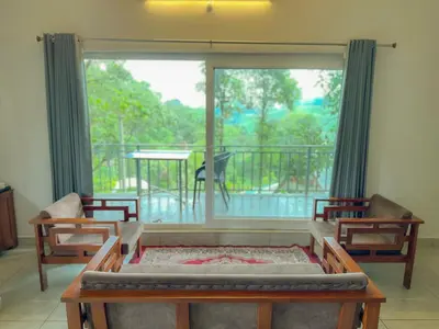 a living room with a large window and a balcony at Forestscape Resort Munnar in Munnar