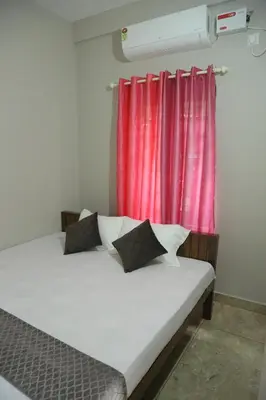 a bed in a room with a red curtain at NR HEAVENZ Near Rajagiri Hospital in Alwaye