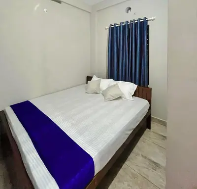 a bed in a room with a blue curtain at NR HEAVENZ Near Rajagiri Hospital in Alwaye