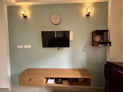 a living room with a clock and a tv on a wall at 1 BHK Fully Furnished - Soorya Madhavam Apartments - Flat No - C2 - Guruvayur, - 150m to North Nada - Family only in Guruvāyūr