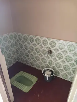 a bathroom with a green toilet in the corner at SHI's Ganga 2BHK in GN Mills, Ganga Hospital, Women's Care Coimbatore in Coimbatore